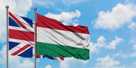 United Kingdom and Hungary flag waving in the wind against white cloudy blue sky together. Diplomacy concept, international relations.