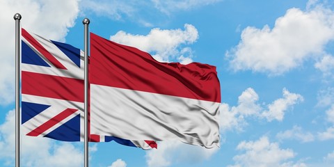 United Kingdom and Indonesia flag waving in the wind against white cloudy blue sky together. Diplomacy concept, international relations.