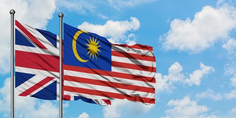 United Kingdom and Malaysia flag waving in the wind against white cloudy blue sky together. Diplomacy concept, international relations.