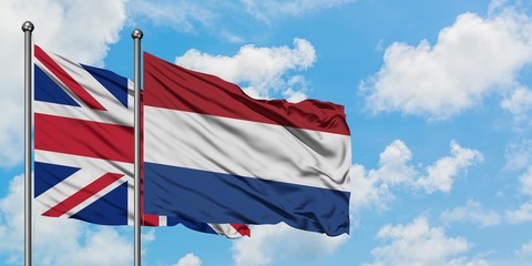 United Kingdom and Netherlands flag waving in the wind against white cloudy blue sky together. Diplomacy concept, international relations.