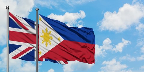 United Kingdom and Philippines flag waving in the wind against white cloudy blue sky together. Diplomacy concept, international relations.