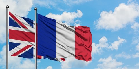 United Kingdom and Reunion flag waving in the wind against white cloudy blue sky together. Diplomacy concept, international relations.