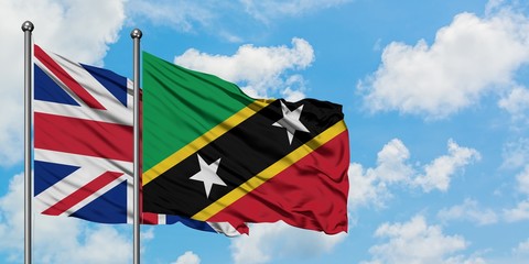 United Kingdom and Saint Kitts And Nevis flag waving in the wind against white cloudy blue sky together. Diplomacy concept, international relations.