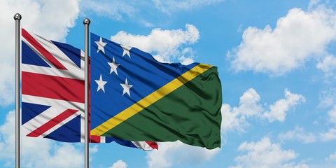 United Kingdom and Solomon Islands flag waving in the wind against white cloudy blue sky together. Diplomacy concept, international relations.