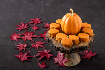 Happy Thanksgiving, small pumpkin cakes, orange ceramic pumpkin on a wooden cake stand, red maple leaves