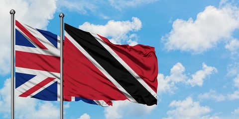 United Kingdom and Trinidad And Tobago flag waving in the wind against white cloudy blue sky together. Diplomacy concept, international relations.