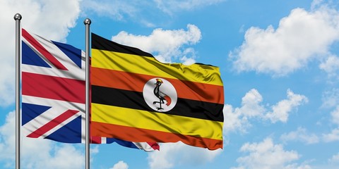 United Kingdom and Uganda flag waving in the wind against white cloudy blue sky together. Diplomacy concept, international relations.