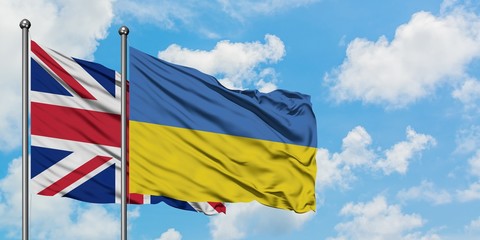 United Kingdom and Ukraine flag waving in the wind against white cloudy blue sky together. Diplomacy concept, international relations.