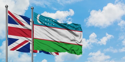 United Kingdom and Uzbekistan flag waving in the wind against white cloudy blue sky together. Diplomacy concept, international relations.