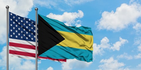United States and Bahamas flag waving in the wind against white cloudy blue sky together. Diplomacy concept, international relations.
