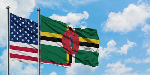 United States and Dominica flag waving in the wind against white cloudy blue sky together. Diplomacy concept, international relations.