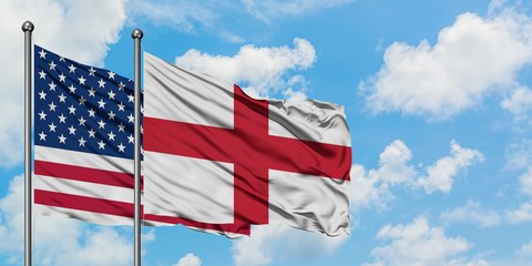 United States and England flag waving in the wind against white cloudy blue sky together. Diplomacy concept, international relations.