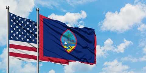 United States and Guam flag waving in the wind against white cloudy blue sky together. Diplomacy concept, international relations. - obrazy, fototapety, plakaty