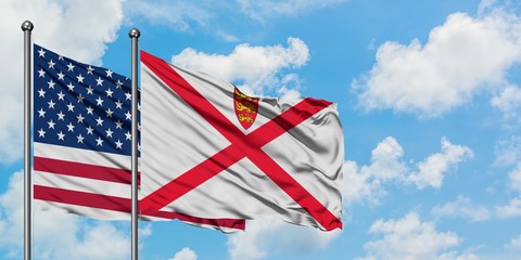 United States and Jersey flag waving in the wind against white cloudy blue sky together. Diplomacy concept, international relations.