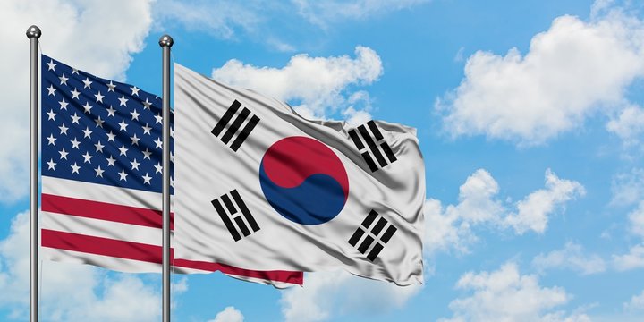 United States and South Korea flag waving in the wind against white cloudy blue sky together. Diplomacy concept, international relations.