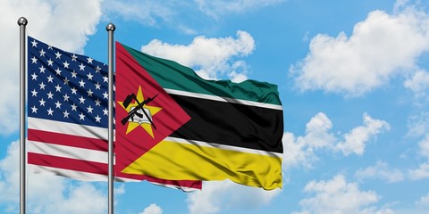 United States and Mozambique flag waving in the wind against white cloudy blue sky together....