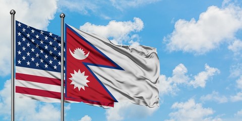 United States and Nepal flag waving in the wind against white cloudy blue sky together. Diplomacy concept, international relations.