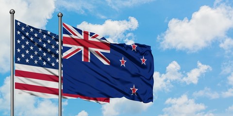 United States and New Zealand flag waving in the wind against white cloudy blue sky together. Diplomacy concept, international relations.