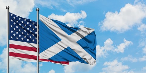 United States and Scotland flag waving in the wind against white cloudy blue sky together. Diplomacy concept, international relations.