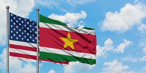 United States and Suriname flag waving in the wind against white cloudy blue sky together. Diplomacy concept, international relations.