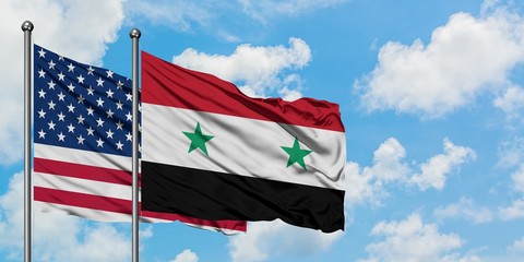 United States and Syria flag waving in the wind against white cloudy blue sky together. Diplomacy concept, international relations.