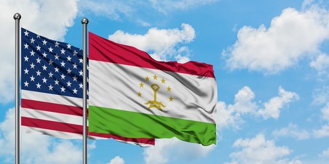 United States and Tajikistan flag waving in the wind against white cloudy blue sky together. Diplomacy concept, international relations.