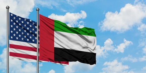 United States and United Arab Emirates flag waving in the wind against white cloudy blue sky together. Diplomacy concept, international relations.