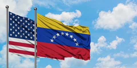 United States and Venezuela flag waving in the wind against white cloudy blue sky together. Diplomacy concept, international relations.