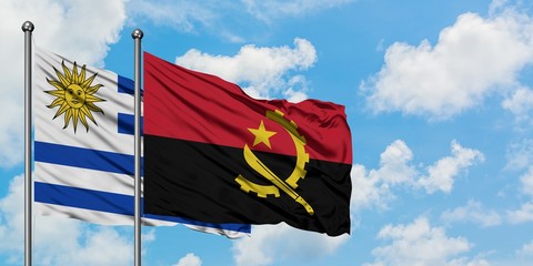 Uruguay and Angola flag waving in the wind against white cloudy blue sky together. Diplomacy concept, international relations.