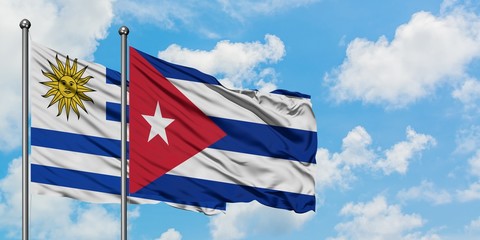 Uruguay and Cuba flag waving in the wind against white cloudy blue sky together. Diplomacy concept, international relations.