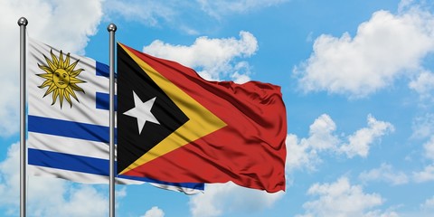 Uruguay and East Timor flag waving in the wind against white cloudy blue sky together. Diplomacy concept, international relations.