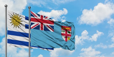 Uruguay and Fiji flag waving in the wind against white cloudy blue sky together. Diplomacy concept, international relations.