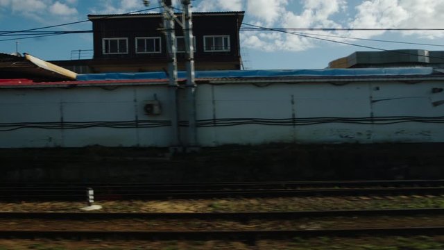 High-speed train moves past an industrial zone in the summer