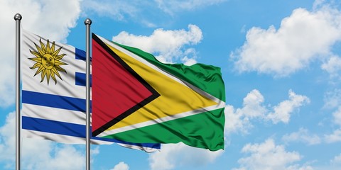 Uruguay and Guyana flag waving in the wind against white cloudy blue sky together. Diplomacy concept, international relations.