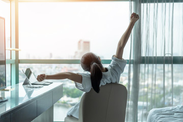 Work-life quality balance concept with happy city lifestyle Asian girl having a good day waking up from sleep in morning taking some rest, lazily relaxing in comfort in condominium or hotel bed room