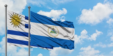 Uruguay and Nicaragua flag waving in the wind against white cloudy blue sky together. Diplomacy concept, international relations.