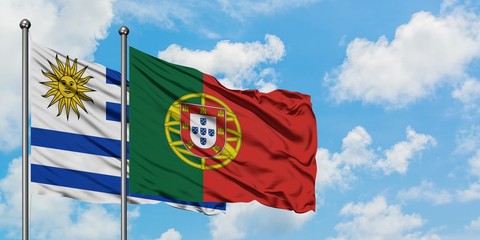 Uruguay and Portugal flag waving in the wind against white cloudy blue sky together. Diplomacy concept, international relations.