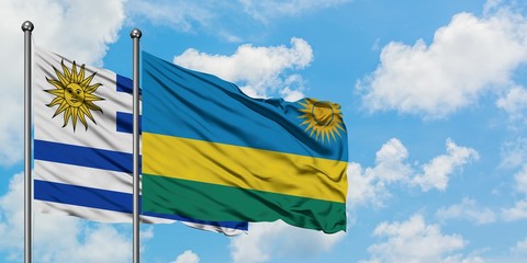 Uruguay and Rwanda flag waving in the wind against white cloudy blue sky together. Diplomacy concept, international relations.