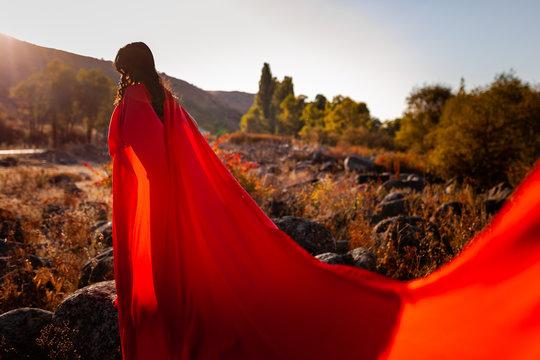 girl from the back in a red cloak in the mountains