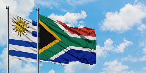 Uruguay and South Africa flag waving in the wind against white cloudy blue sky together. Diplomacy concept, international relations.