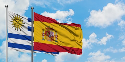 Uruguay and Spain flag waving in the wind against white cloudy blue sky together. Diplomacy concept, international relations.