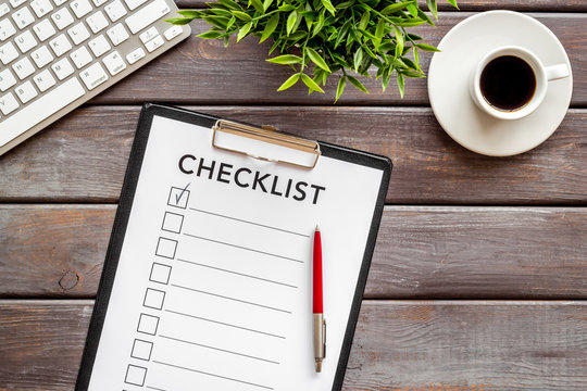 Checklist on dark wooden office background top view