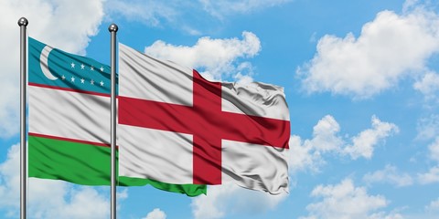 Uzbekistan and England flag waving in the wind against white cloudy blue sky together. Diplomacy concept, international relations.