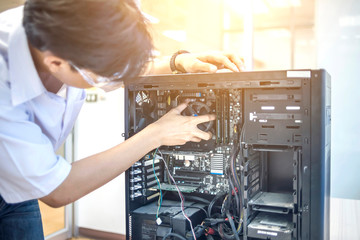 Male motherboard repairer using a screwdriver to replace the motherboard Concept of computer repair, close-up view of hardware