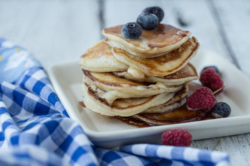 Tasty breakfast. Homemade pancakes with crushed berry, honey or maple syrup on white grey  background.