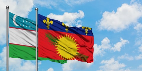 Uzbekistan and Guadeloupe flag waving in the wind against white cloudy blue sky together. Diplomacy concept, international relations.