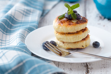 Cottage cheese pancakes with sour cream and tea. Gourmet Breakfast - Cottage cheese pancakes, syrniki, curd fritters in a white plate. Russian syrniki or sirniki, cottage cheese fritters.