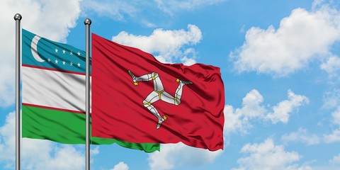 Uzbekistan and Isle Of Man flag waving in the wind against white cloudy blue sky together. Diplomacy concept, international relations.