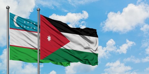 Uzbekistan and Jordan flag waving in the wind against white cloudy blue sky together. Diplomacy concept, international relations.