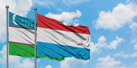 Uzbekistan and Luxembourg flag waving in the wind against white cloudy blue sky together. Diplomacy concept, international relations.